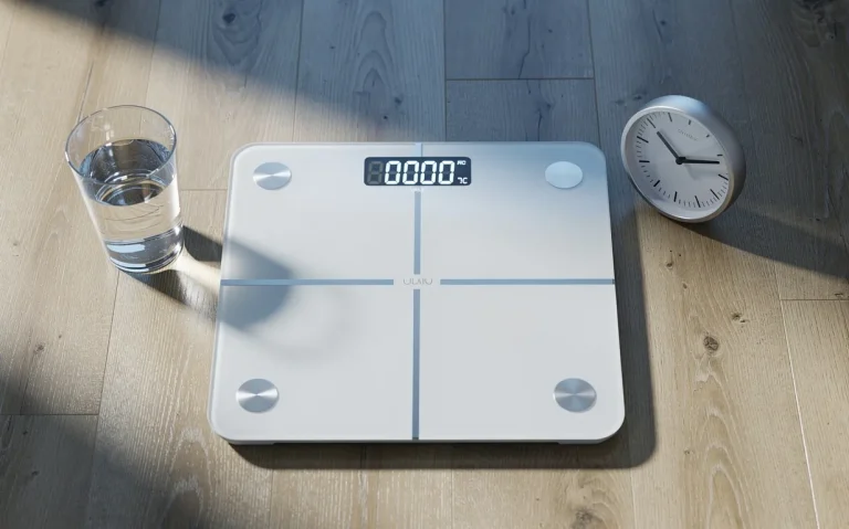 Une balance digitale affichant un poids réduit posée sur un parquet, accompagnée d’un verre d’eau et d’une horloge dans une lumière matinale.