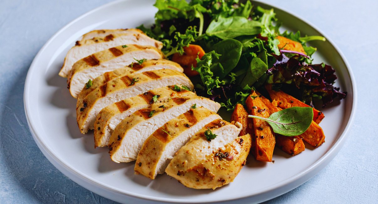 Assiette de poulet grillé accompagnée de salade et légumes rôtis