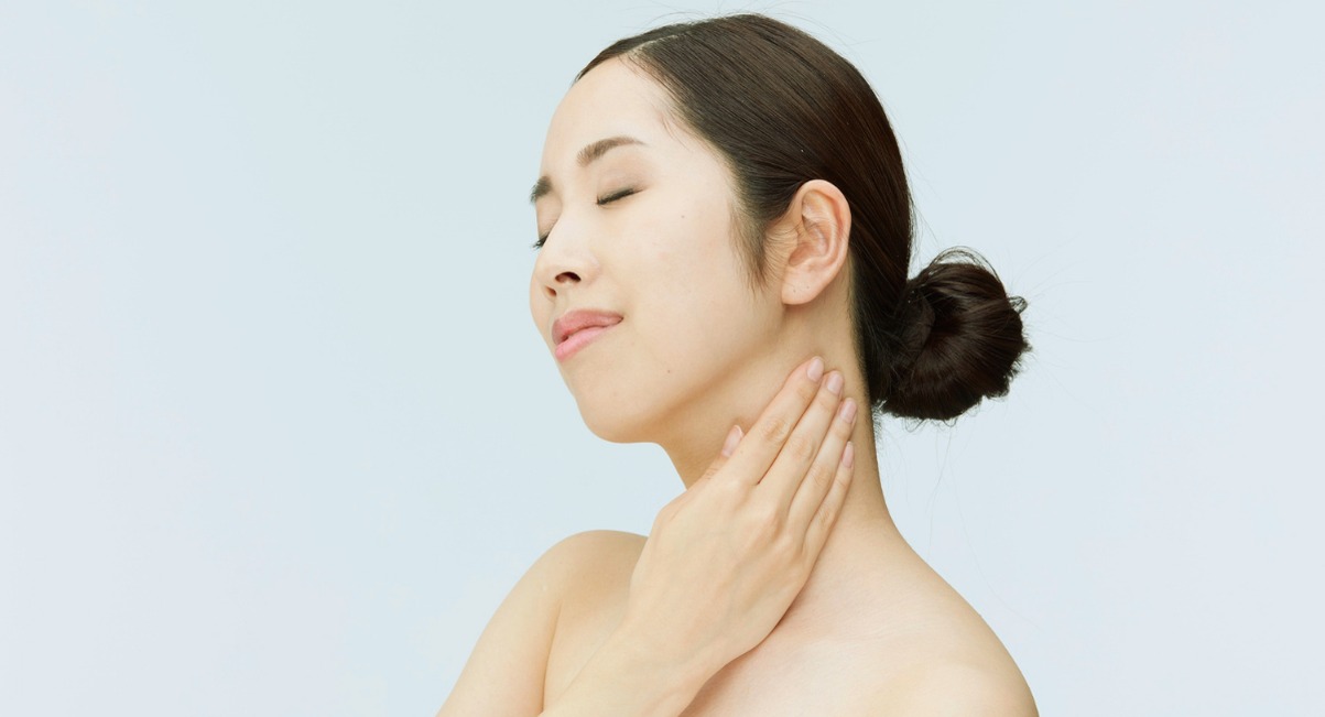 Femme touchant doucement sa gorge en signe d'apaisement