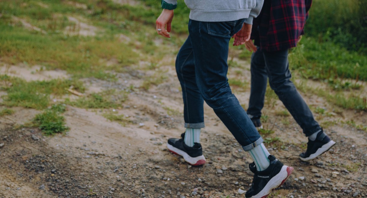 Jambes de personnes marchant en baskets sur un chemin de terre
