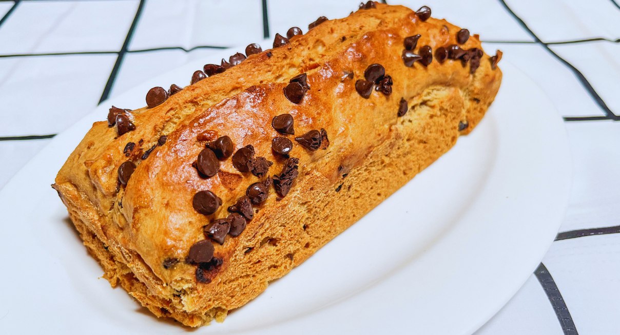 Cake maison doré parsemé de pépites de chocolat sur une assiette