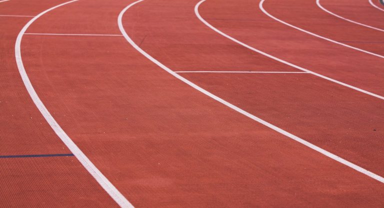 Piste d'athlétisme rouge courbée avec lignes de couloir blanches