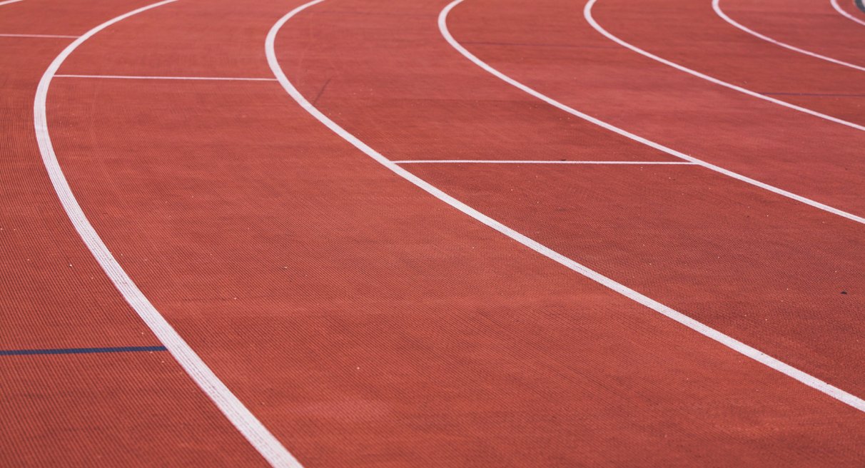 Piste d'athlétisme rouge courbée avec lignes de couloir blanches