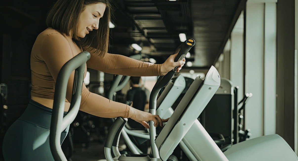 Femme s'entraînant sur un vélo elliptique dans une salle de sport